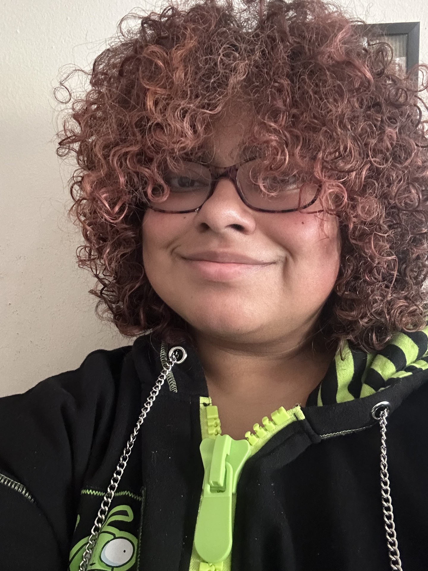 Photo of Axel Garcia, a BIPOC person with brown, natural short curly hair and bangs that cover their forehead and partially obscure their glasses.