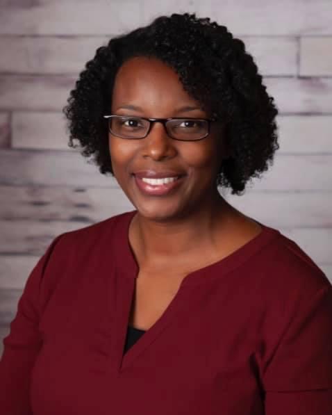 Photo of a Black woman with short natural hair, glasses, and a red long-sleeve top.